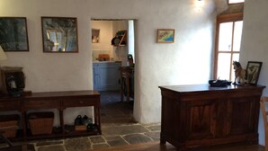 Ein rustikales Interieur mit Holzdielen, einem Esstisch und einer Küche im Hintergrund.