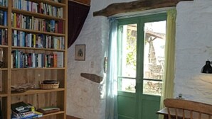 Ein Zimmer mit einer Holzhülle voller Bücher, einer grünen Tür und einem rustikalen Deckenbalken.