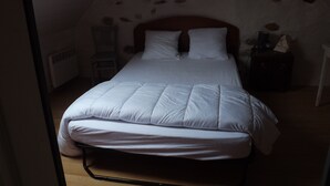 A single bed in a room with a sloped ceiling and exposed stone walls. - Breton house 2 bedrooms bathroom / living room / kitchen (Ploezal)