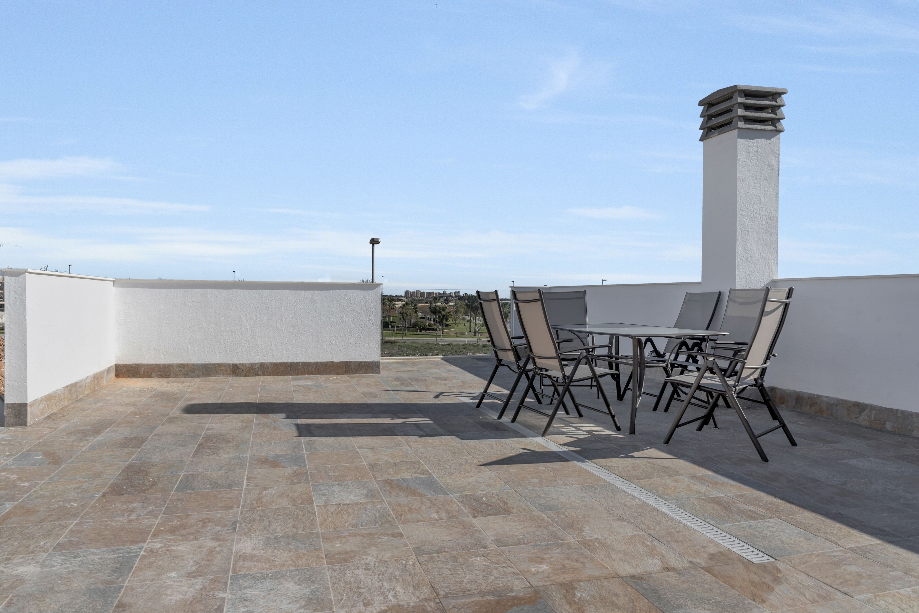Una terraza en la azotea con una mesa, sillas, una chimenea y vistas despejadas del entorno.