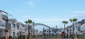 Stunning residential area with modern architecture, featuring white buildings with balconies and a striking metal archway.
