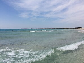 A beach with clear water, waves, and a distant shoreline with buildings. - Villa Giovanna in Santa Caterina di Nardò (Santa Caterina Nardò)