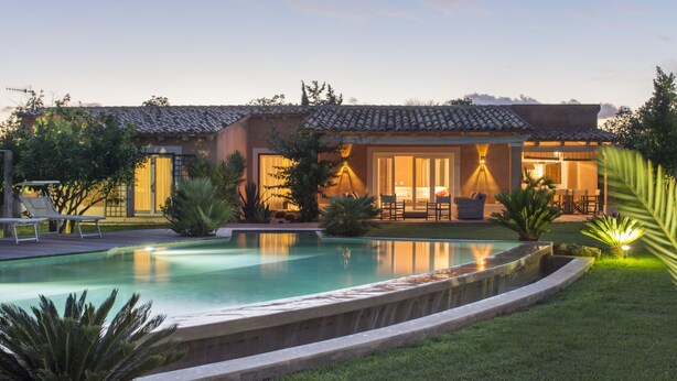 Ein modernes Haus mit Swimmingpool, Sitzgelegenheiten im Freien und einem gepflegten Garten.