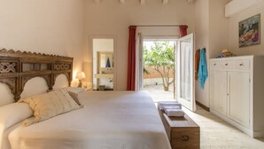 Ein Schlafzimmer mit einem großen Bett, einem hölzernen Kopfteil, einem Kleiderschrank und Blick ins Freie.