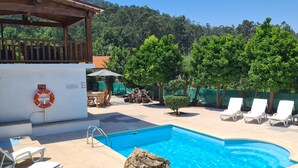 A pool area with lounge chairs and a lifebuoy on a white wall. - Beautiful detached villa with private pool, FibreWi-fi, garden, games room & BBQ (Souto)