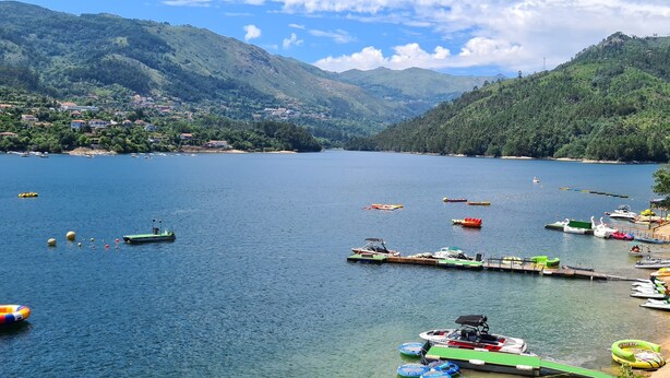 A lake with boats, a dock, and a beach with umbrellas. - Beautiful detached villa with private pool, FibreWi-fi, garden, games room & BBQ (Souto)