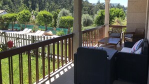 A covered outdoor area with a wooden deck, lounge chairs, and a table. - Beautiful detached villa with private pool, FibreWi-fi, garden, games room & BBQ (Souto)