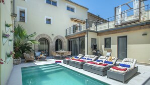 A poolside area with lounge chairs, a dining table, and a small garden.