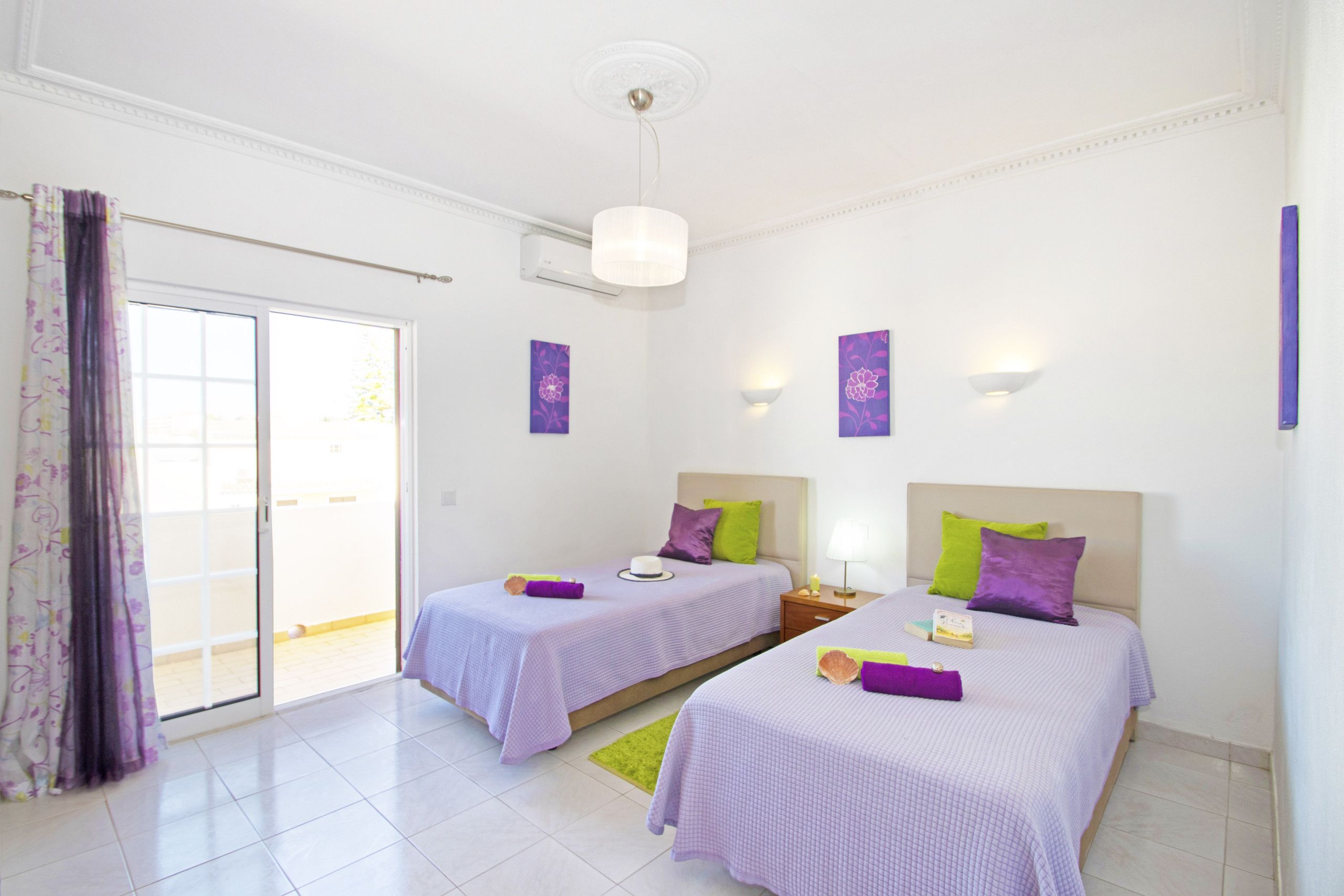 A hotel room with two beds, a sliding glass door, and a ceiling fan.