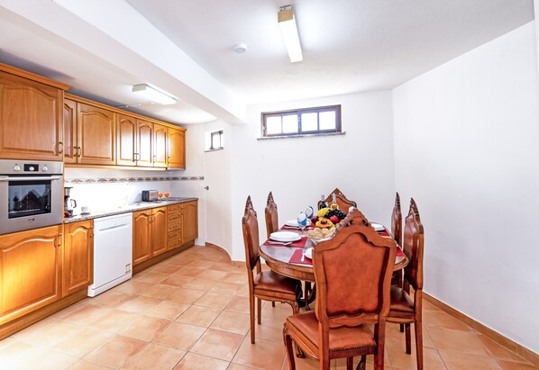A kitchen with wooden cabinets, a built-in oven, and a dining area with a table set for two.