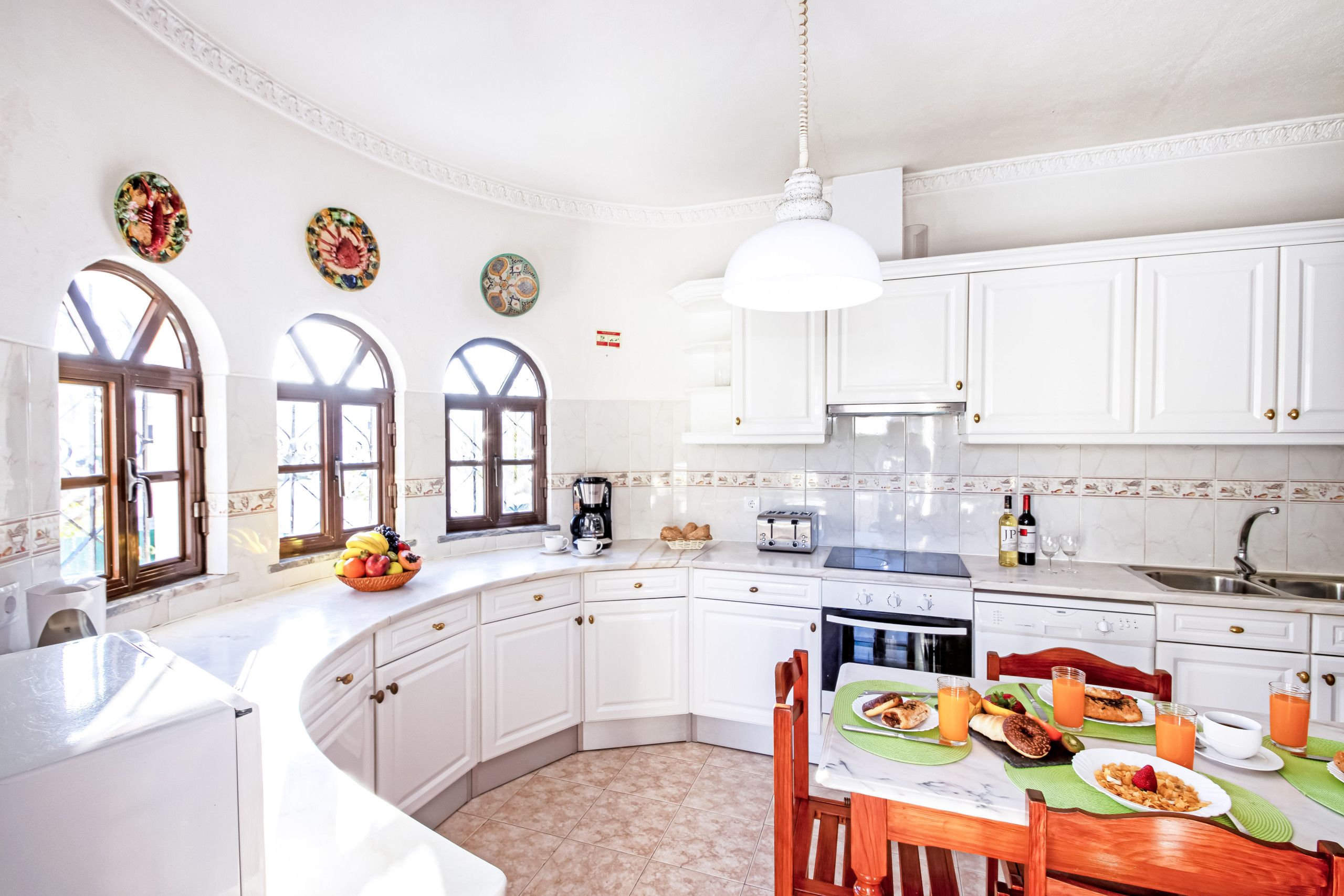 A kitchen with white cabinets, a dining table set for breakfast, and a coffee maker.