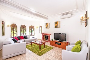 A modern living room with a white sofa, a coffee table, a TV, and a fireplace.