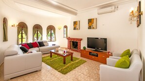 A spacious living room with a fireplace, a television, and comfortable seating. - Family retreat with heatable pool and BBQ (Albufeira)