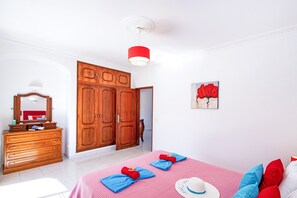 Une chambre à coucher avec un lit, une commode, une armoire et un tableau accroché au mur.