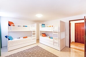 A room with two bunk beds, a wooden door, and a patterned rug.