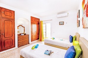 A hotel room with two beds, wooden wardrobes, a mirror, and a painting on the wall.