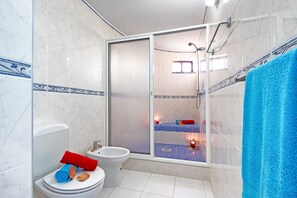 Een bad/douchecombinatie, een haardroger, handdoeken