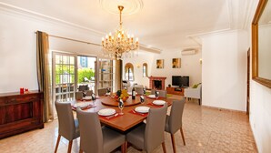 A dining room with a chandelier, a fireplace, and a television in the background. - Family retreat with heatable pool and BBQ (Albufeira)