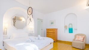 Ein Schlafzimmer mit Bett, Kommode, Stuhl und Traumfänger.