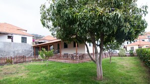 Une maison avec un toit en tuiles, une clôture en bois et une pelouse bien entretenue.