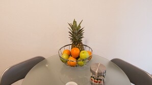 Une table à manger avec un panier de fruits, deux tasses et une grande tasse.