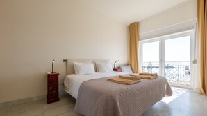 Een slaapkamer met een groot bed, een nachtkastje en een raam met gordijnen.