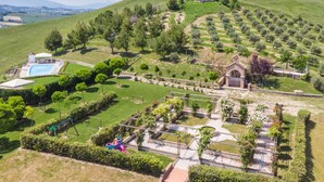 Vista aérea de una propiedad con piscina, una pequeña capilla y un parque infantil.