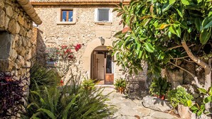 Un bâtiment en pierre avec un toit recouvert de tuiles, une porte en bois et une petite fenêtre.