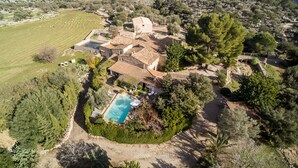 Une villa dotée d’une piscine, entourée d’une végétation luxuriante et d’oliviers, avec en toile de fond un paysage montagneux.
