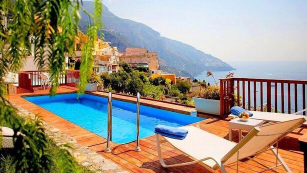 A pool area with a view of the sea and mountains.