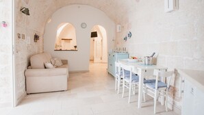 A cozy, stone-walled room with a sofa, dining table, and chairs.
