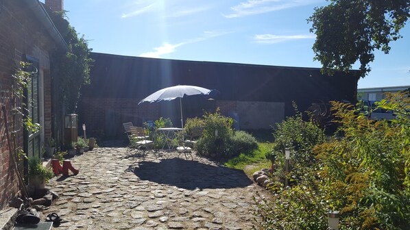 Relax in a serene courtyard setting surrounded by lush greenery and a shaded seating area.