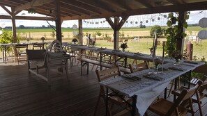 Enjoy a meal under the shade of a pergola with a view of the surrounding field and trees.