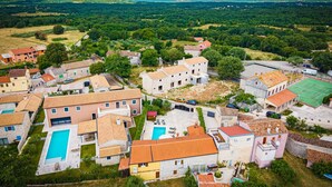 Vista aérea de una zona residencial con casas, una piscina y una cancha de tenis.