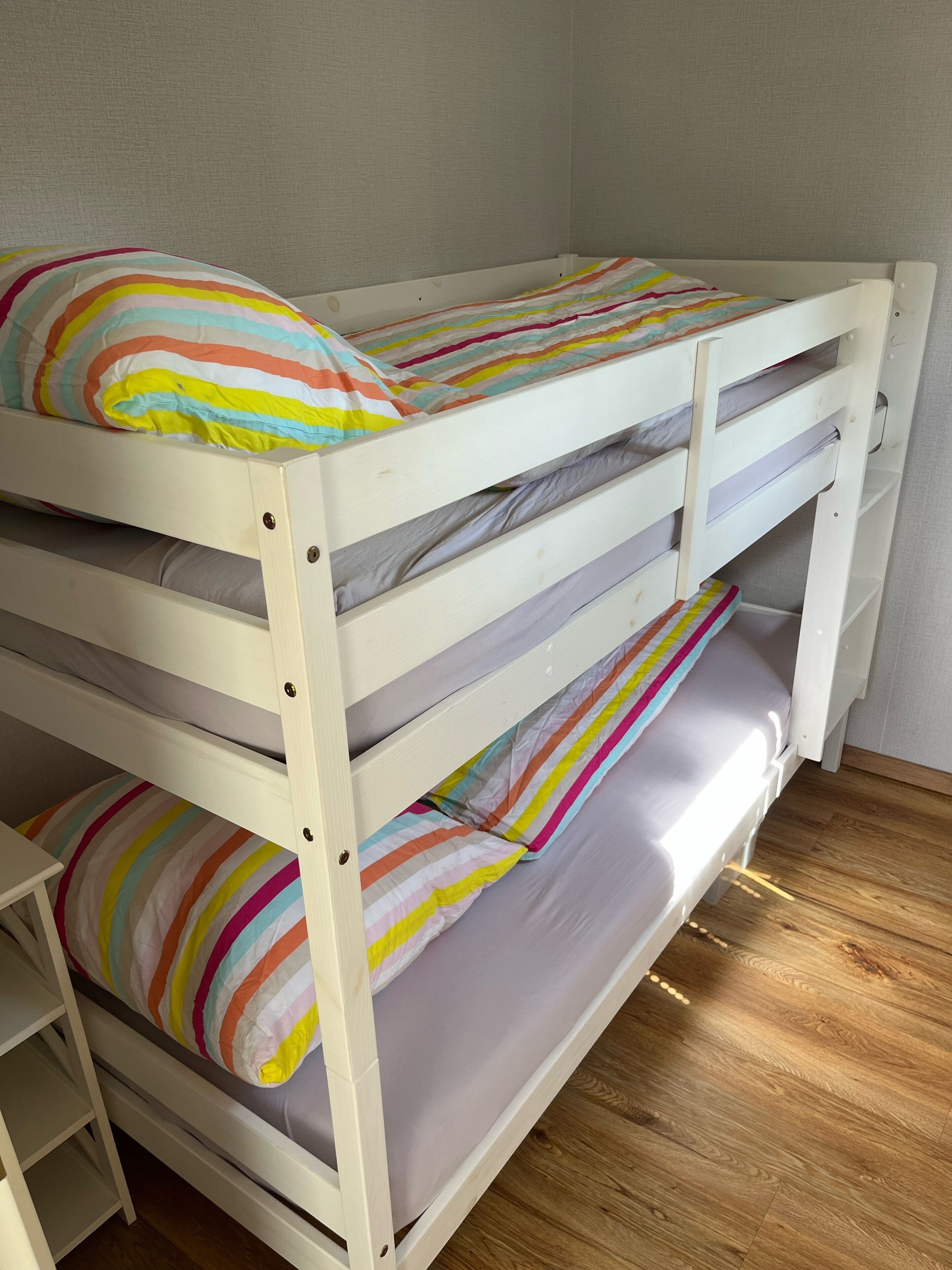 Een stapelbed met gestreepte beddengoed en een witte muur.