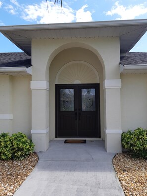 A house with a dark front door, an arched entrance, and a covered porch. - Last minute deal available (Cape Coral)