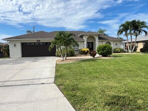 A residential house with a garage, a driveway, and a well-maintained lawn.