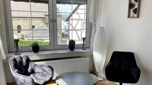 Um quarto com uma janela grande, uma mesa redonda, duas cadeiras e um radiador.