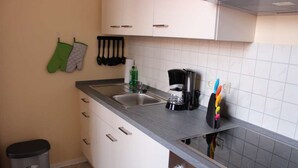 A kitchen with a sink, a coffee maker, and a trash bin. - Apartment 3 - 3 Bedrooms - 110 m² - Wifi - Dog allowed (Wernigerode)