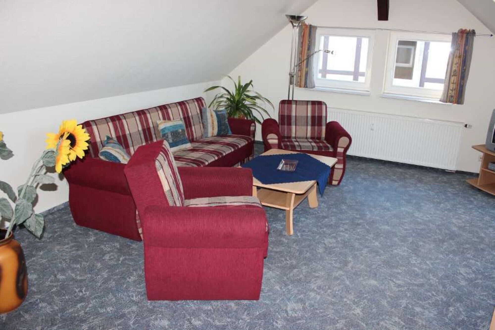 A living room with a red sofa, a red armchair, a blue coffee table, and a potted plant.