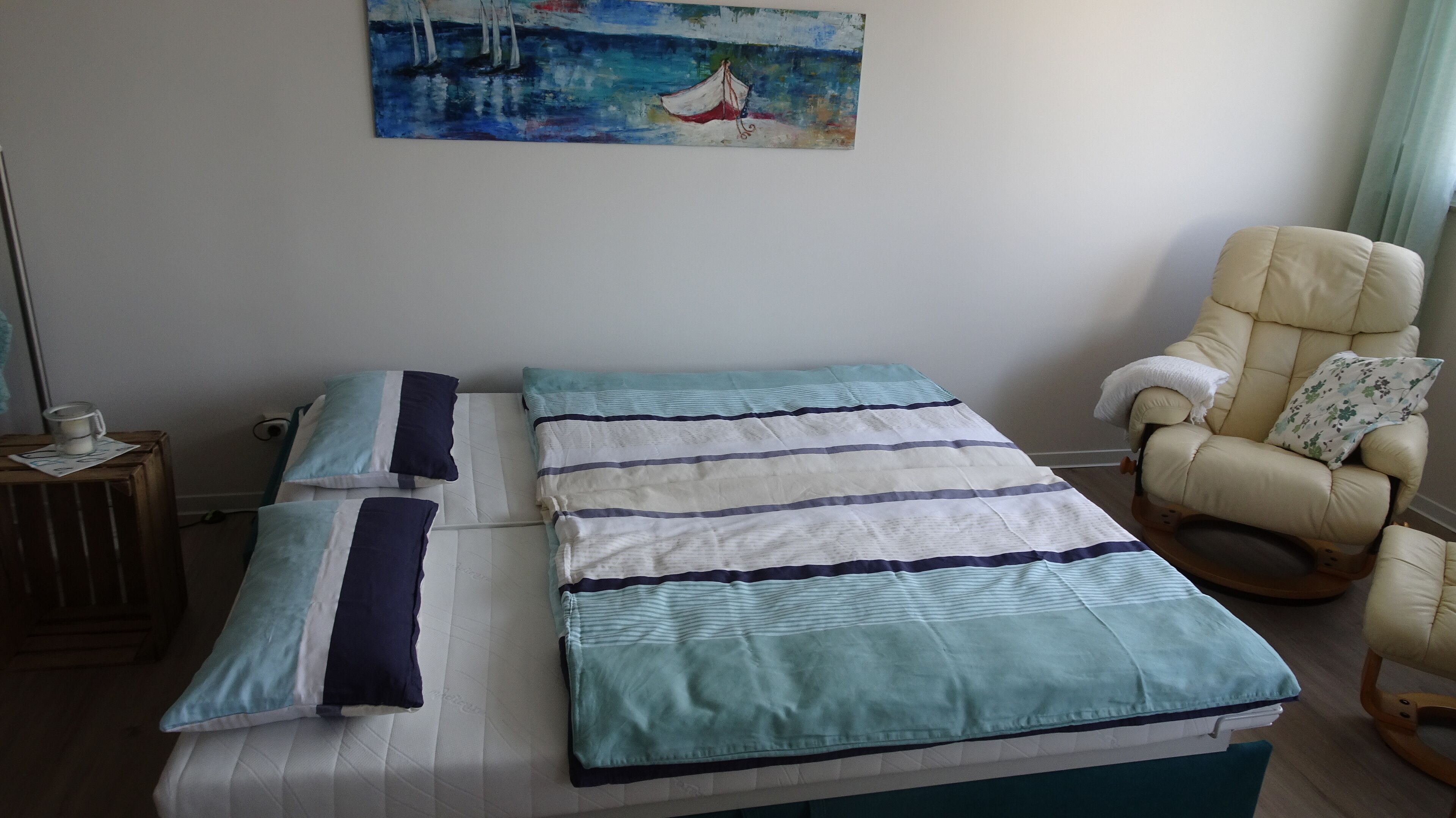 A bedroom with a bed, pillows, a chair, and a painting on the wall.