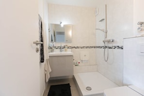 Une salle de bain moderne équipée d’une douche, de toilettes, d’un lavabo et d’un miroir.