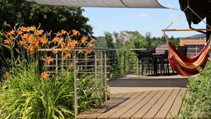 A wooden deck with a metal railing, a hammock, and a table and chairs set up for outdoor dining. - Comfortable wooden house in the heart of Saxon Switzerland above Rathen (Bad Schandau OT Waltersdorf)