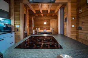 Eine moderne Küche mit Kochinsel, Holzwänden und einem Essbereich mit Tisch und Stühlen.