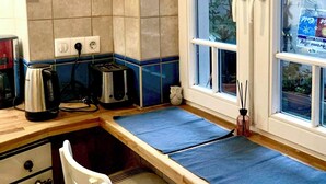 A kitchen with a window, a stove, a toaster, and a decorative plate on the wall.