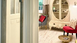 A room with a white door, a red armchair, a white cabinet, and a small table with a book.