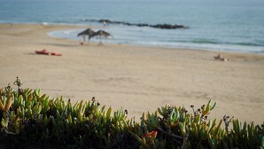 A beach with a clear view of the ocean, a sandy shore, and some vegetation in the foreground. - Small, modern beach house on the sand, quiet,sea view, WiFi, aircon, max. 7 p. (Donnalucata)