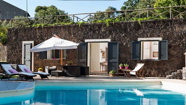 A poolside area with lounge chairs, a covered seating area, and a stone wall. - Monte - Independent House with private Pool, 4 People, Garden WiFi, A/C, Sicily (Ragalna)