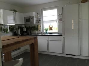 Une cuisine moderne avec des meubles blancs, une table en bois, un évier et une fenêtre donnant sur un beau paysage.