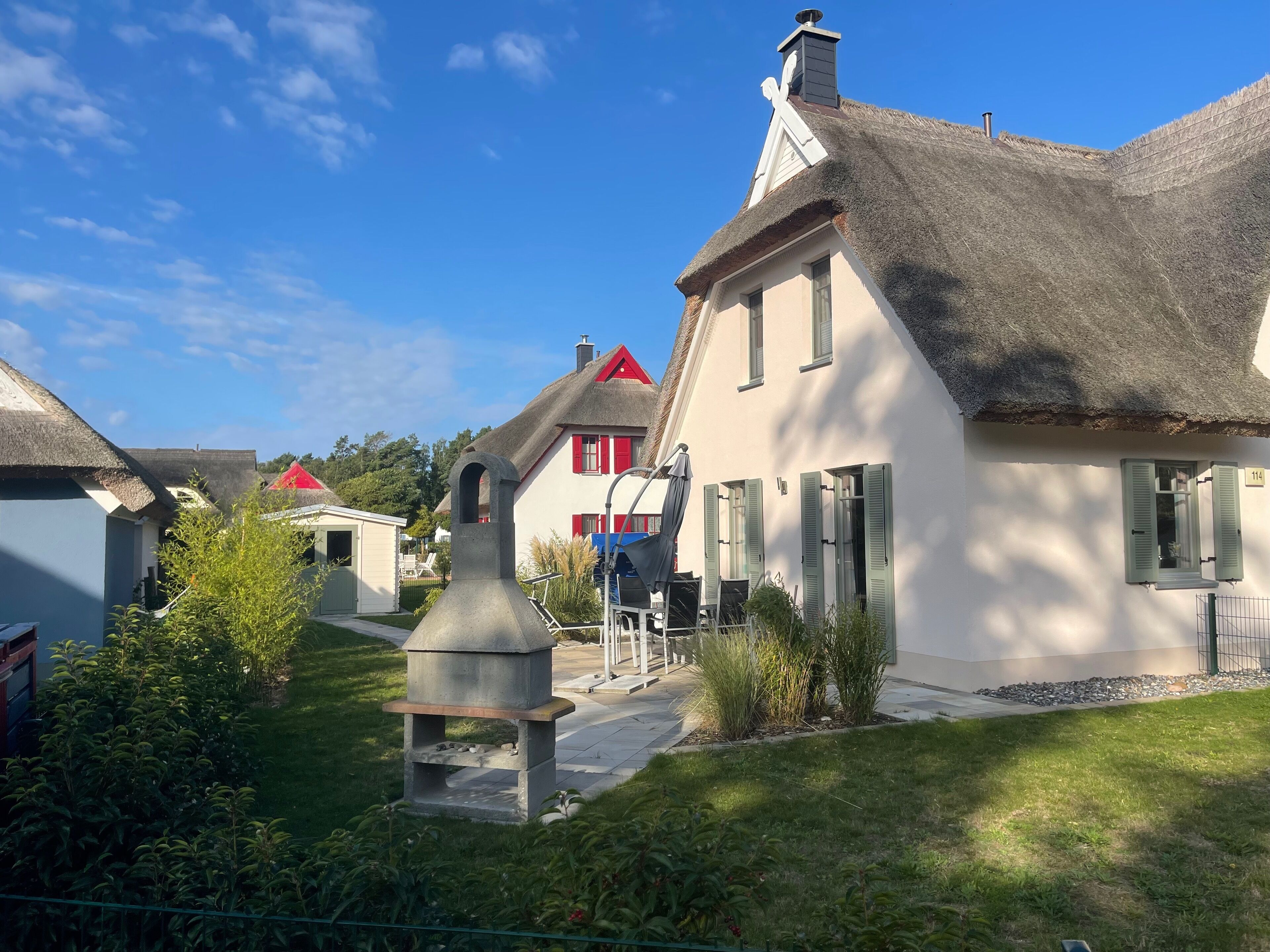 Un village européen traditionnel, avec ses maisons aux toits de chaume, son four communal central et un jardin bien entretenu.